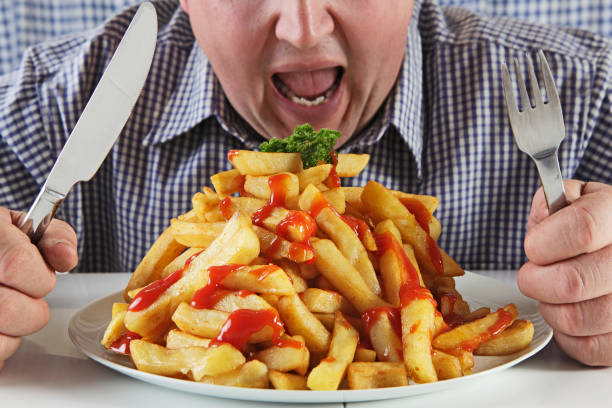 man eating very large plate of fries - junk food stock pictures, royalty-free photos & images