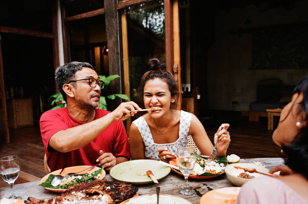 man feeding snack to woman at dining table - food stock pictures, royalty-free photos & images