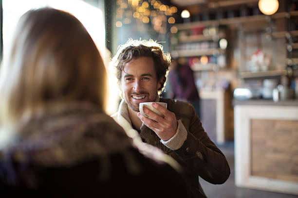 man having coffee while looking at woman in cafe - coffee stockfoto's en -beelden