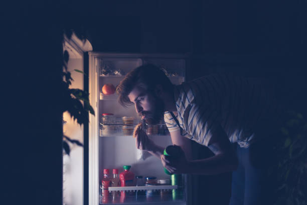 man having snack and drinking beer late night in front of the refrigerator - junk food stock pictures, royalty-free photos & images