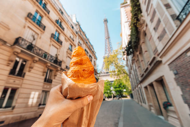 man holding croissant next to eiffel tower, personal perspective view, paris, france - food stock pictures, royalty-free photos & images