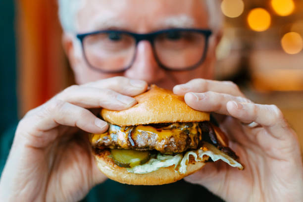 man holding delicious fresh flame grilled burger in restaurant - junk food stock pictures, royalty-free photos & images