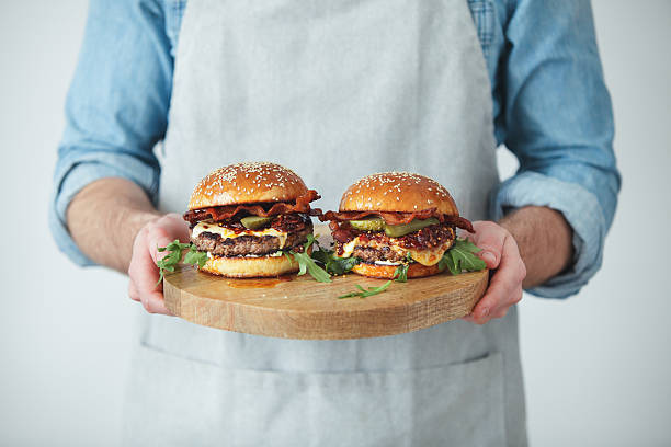 man holding homemade angus beef burgers with bacon whisky jam - junk food stockfoto's en -beelden