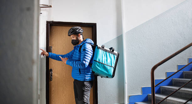 man indoors by front door in block of flats, food delivery and coronavirus concept. - food stock pictures, royalty-free photos & images