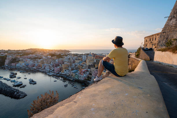 man looking at procida cityscape at sunset, gulf of naples, italy - travel stock pictures, royalty-free photos & images