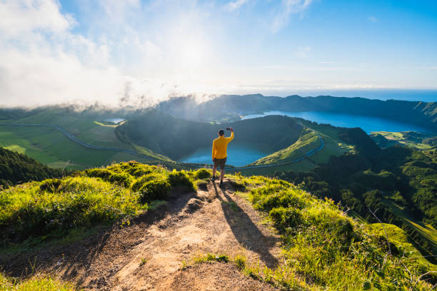 man on top of a mountain photographing volcanoes in sao miguel, azores - travel stock pictures, royalty-free photos & images