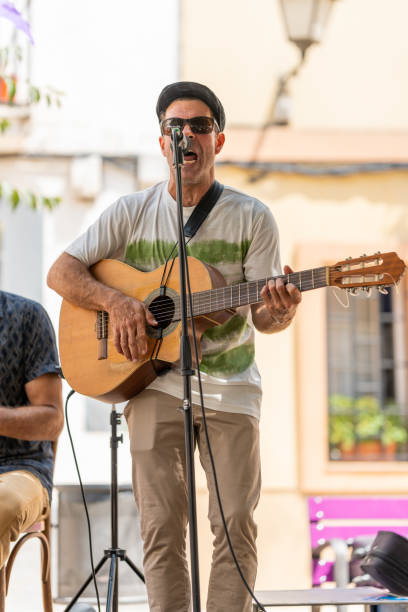 man playing a guitar and singing while performing on an outdoor stage. - concert stock pictures, royalty-free photos & images