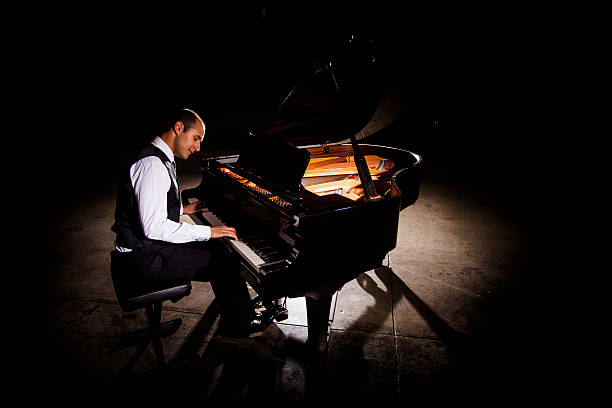 man playing piano with dramatic lighting - concert stock pictures, royalty-free photos & images