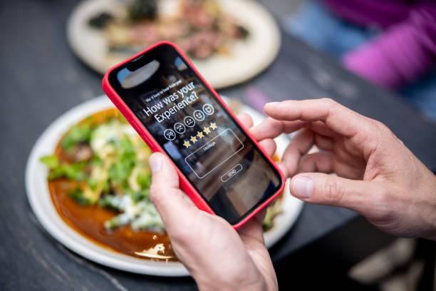 man rating his experience at a restaurant using an app on a cell phone - food stock pictures, royalty-free photos & images