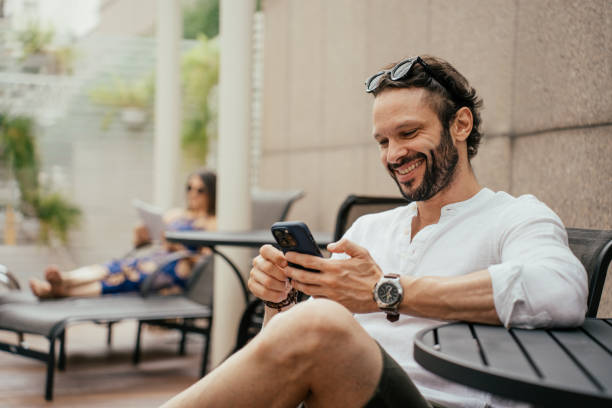 man relaxing by the pool using smartphone - travel stock pictures, royalty-free photos & images