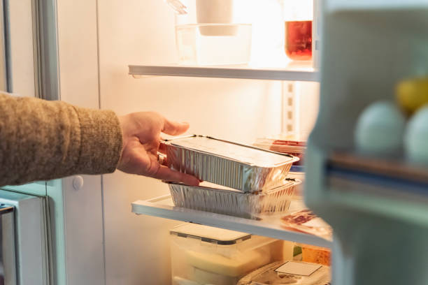 man's hand taking takeout meal out of refrigerator. - junk food stock pictures, royalty-free photos & images