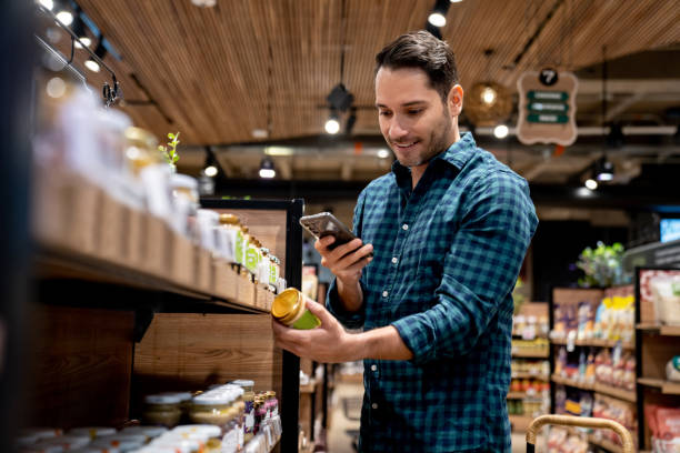 man shopping at the supermarket and scanning a label with his cell phone - food stock pictures, royalty-free photos & images