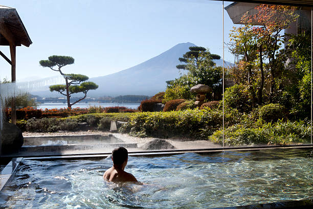man soaking in an indoor hot spring pool - travel stock pictures, royalty-free photos & images
