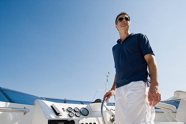 man steering a yacht - fashion stock pictures, royalty-free photos & images