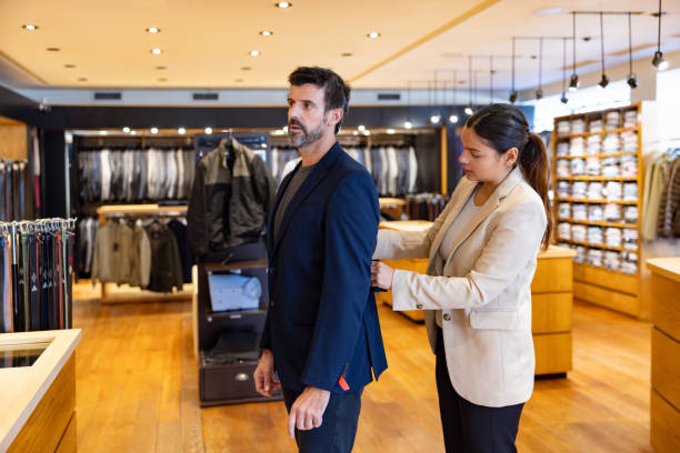 man trying on a suit at a clothing store - fashion stock pictures, royalty-free photos & images