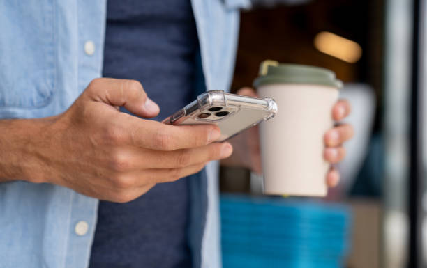 man using his phone and drinking coffee on the go - junk food stock pictures, royalty-free photos & images