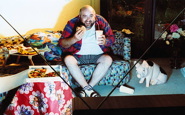 man watching tv and eating junk food - junk food stock pictures, royalty-free photos & images