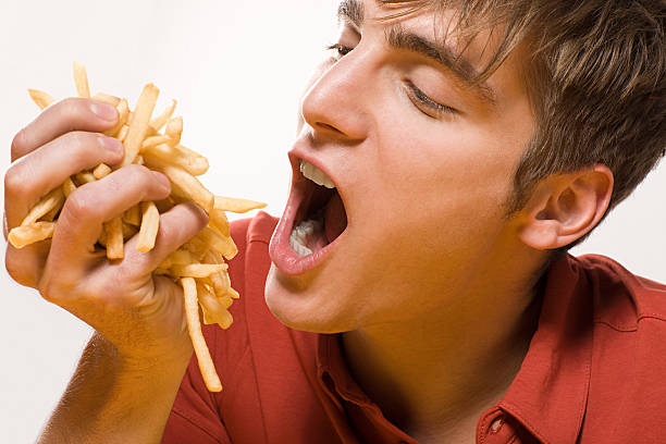 man with handful of fries - junk food stock pictures, royalty-free photos & images