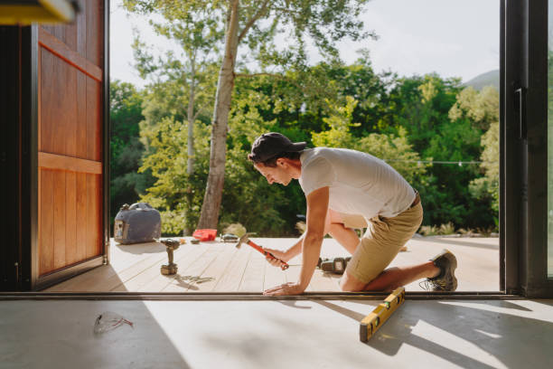 man working on wooden decking in front of a cabin house - home decoration stock pictures, royalty-free photos & images