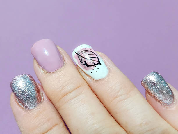 manicured hand, light pink and silver nail polish with a leaf design - nails art stock pictures, royalty-free photos & images