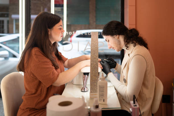 manicurist is giving a manicure to a customer in a beauty salon - nails art photos et images de collection