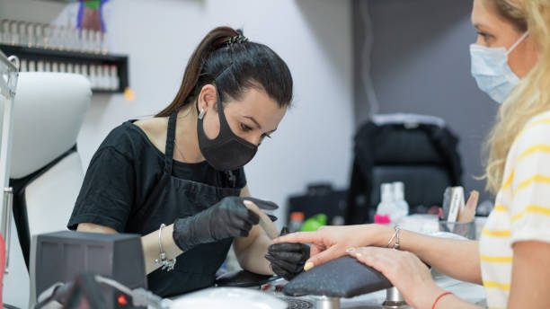 manicurist using an electric nail file to remove cuticles in the beauty salon - nails art stock pictures, royalty-free photos & images