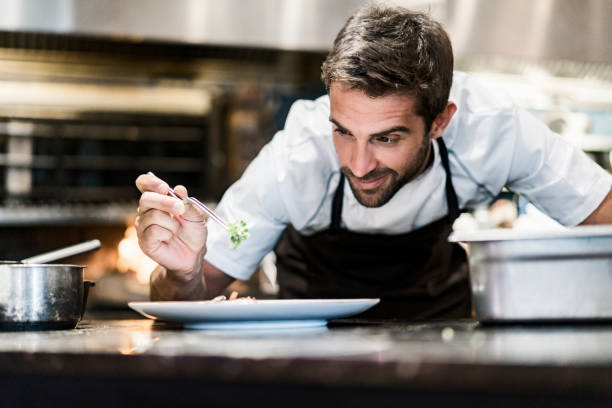 mannelijke chef-kok bijgerechten van voedsel in de keuken - food stockfoto's en -beelden
