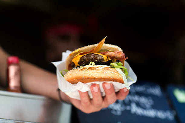 mans hand serving hamburger from fast food van - junk food stock pictures, royalty-free photos & images