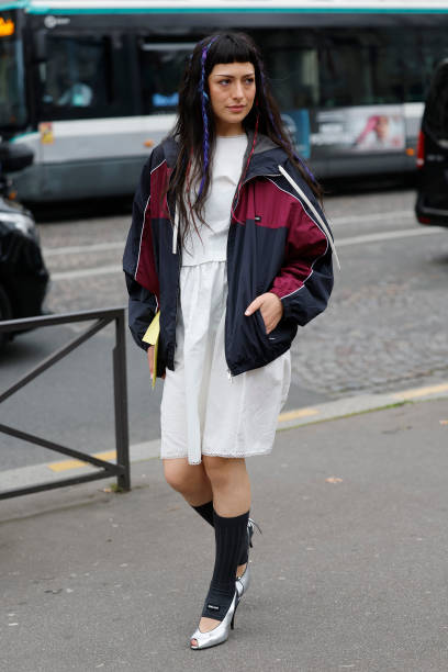Maria Bottle wears white midi dress, blue and red Miu Miu jacket, grey Miu Miu socks, silver heels, outside Miu Miu, during the Womenswear...