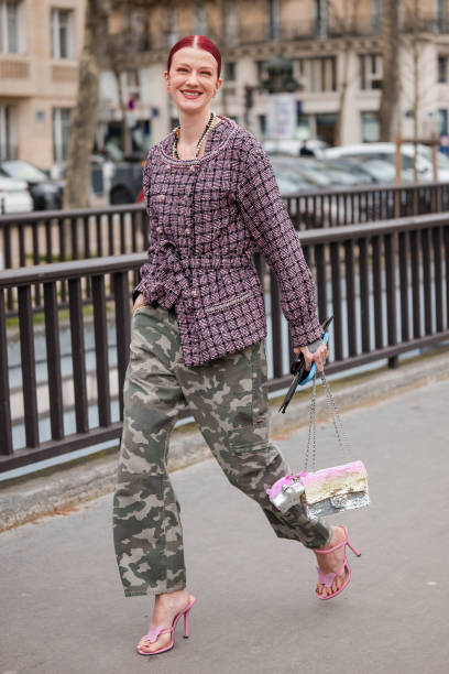 Marianne Theodorse wears pink tweed jacket, military print pants, sequins Chanel bag, pink heels, outside Chanel, during the Womenswear Fall/Winter...