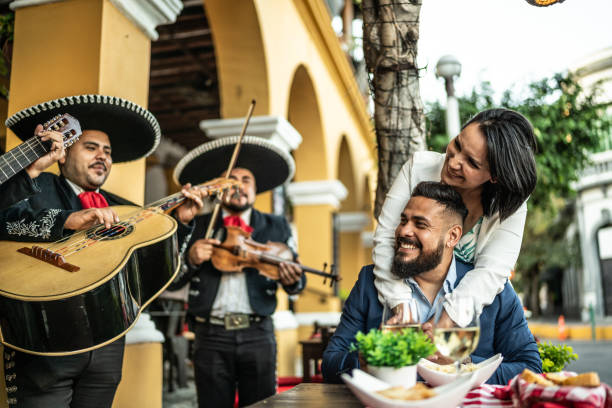 married couple listening to mariachi music at a restaurant outdoors - food stock pictures, royalty-free photos & images