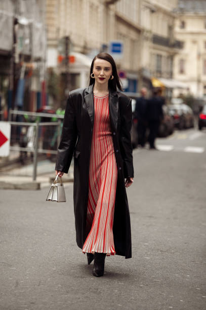 Mary Leest wears striped red and grey long maxi dress, black shoes, black coat and white Hermes bag outside Akris during the Womenswear Fall/Winter...