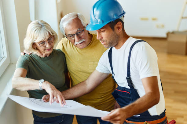 mature couple examining blueprints with manual worker in the apartment. - home decoration stock pictures, royalty-free photos & images