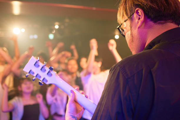 mature japanese guitarist performing on stage at music concert. - concert stock pictures, royalty-free photos & images