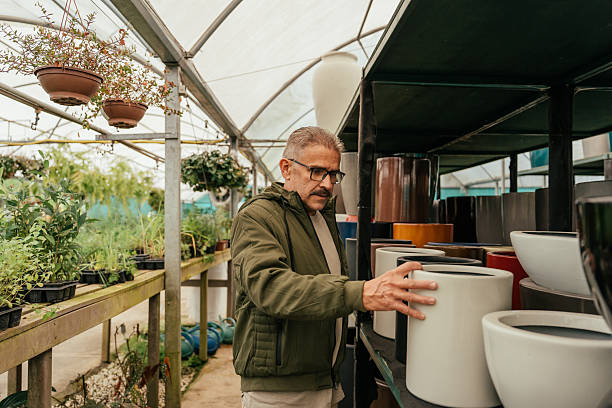 mature man choosing flower pots in flower shop - garden decoration stock pictures, royalty-free photos & images