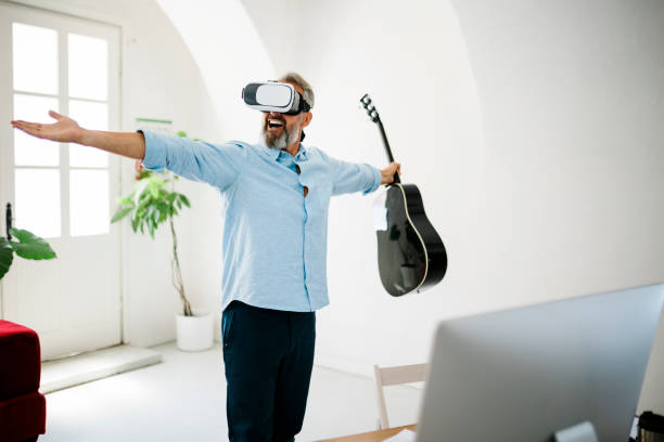 mature man playing the acoustic guitar in virtual reality glasses at the office - concert stock pictures, royalty-free photos & images