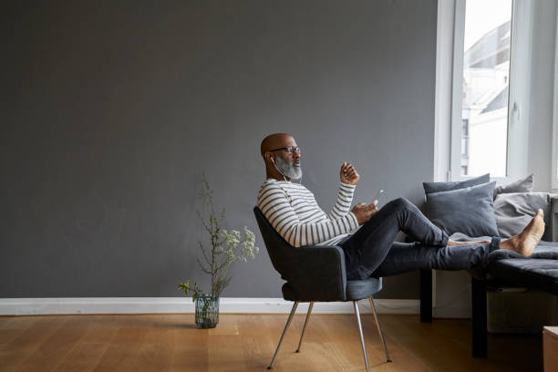 mature man sitting with feet up, using smartphone - fashion photos et images de collection