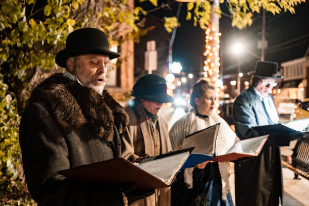 mature people singing christmas carols outdoors at night - concert stock pictures, royalty-free photos & images