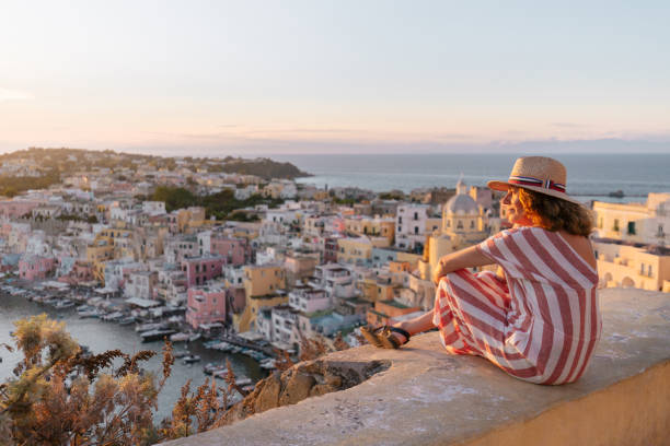 mature woman admiring procida sunset cityscape - travel stock pictures, royalty-free photos & images