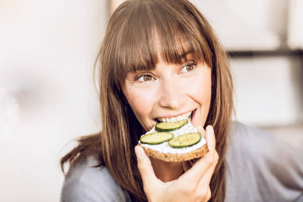 mature woman eating healthy cucumber bread - food photos et images de collection