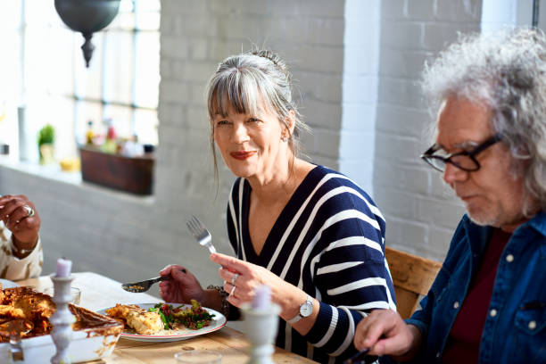 mature woman enjoying healthy lunch with friends - food stockfoto's en -beelden