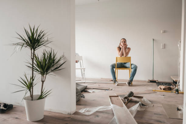 mature woman moving house, sitting on chair - home decoration stockfoto's en -beelden