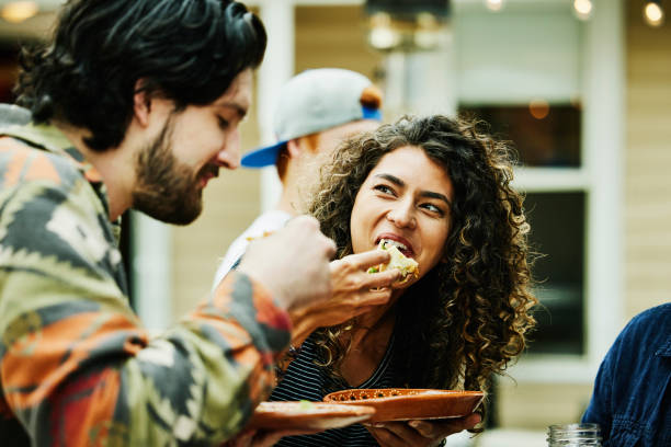 medium close up shot of woman eating tacos with friends at food truck - food stock pictures, royalty-free photos & images