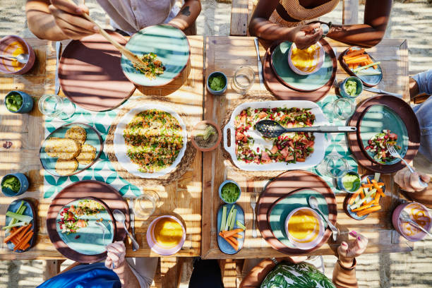 medium overhead shot of friends sharing lunch at outdoor table - food stock pictures, royalty-free photos & images