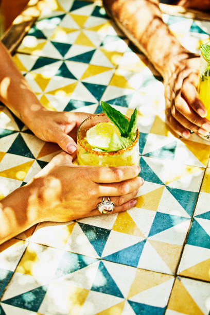 medium shot of womans hands holding margarita at table in beach cafe - food stock pictures, royalty-free photos & images