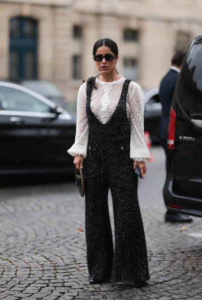 Mehrnaz Ansari is seen outside Chanel show wearing black Chanel sunnies, pearl earrings, white lace top with long sleeves, black Chanel tweed...
