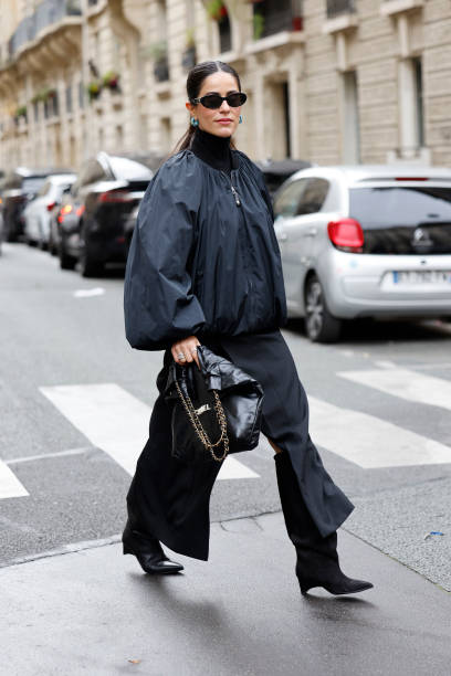 Mehrnaz Ansari wears black bomber jacket, black long skirt, black Chanel bag, black boots, black Chanel sunglasses, outside Stella McCartney, during...