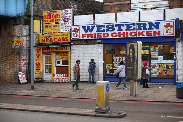 Members of the public walk past a mini-cab kiosk and a fst food fried chicken outlet near Lewisham high street on December 5, 2012 in London,...