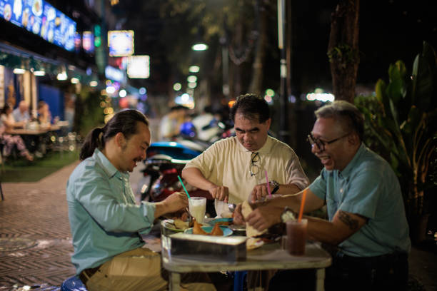 men eating authentic thai food at the night market - junk food stock pictures, royalty-free photos & images