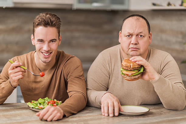 men eating in the kitchen and looking at camera. - junk food stock pictures, royalty-free photos & images